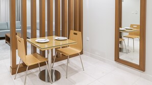 Un comedor moderno con una mesa de vidrio, sillas de madera y un espejo grande en la pared.