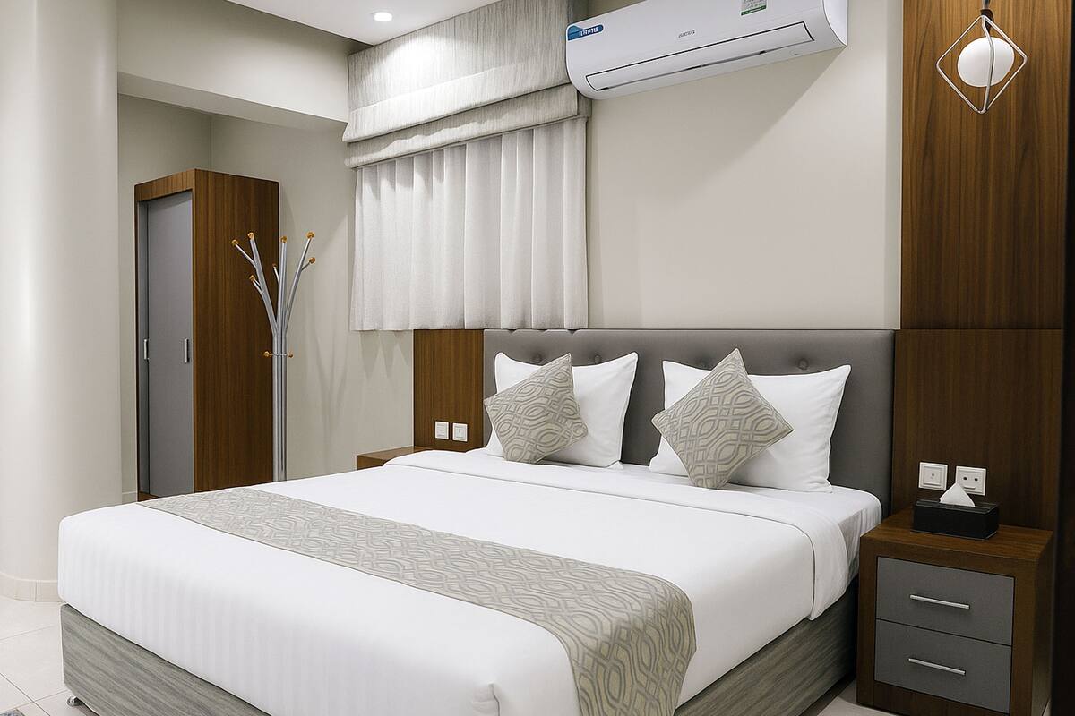 Un dormitorio de hotel moderno con una cama grande, una mesita de noche y un equipo de aire acondicionado.