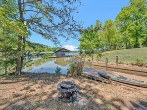 Un chalet au bord du lac, doté d’une jetée qui s’avance sur l’eau, entouré d’arbres et d’une zone herbeuse.