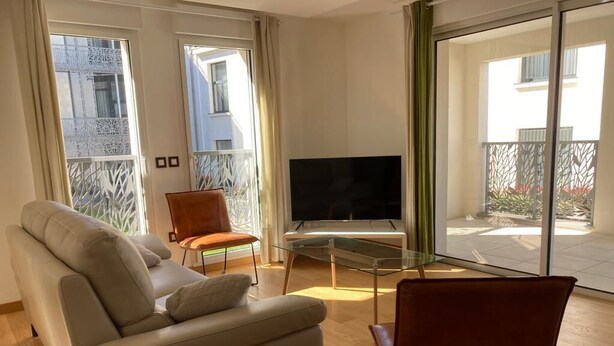 Ein modernes Wohnzimmer mit einer Couch, einem Glastisch, einem Fernseher und einem Sessel.