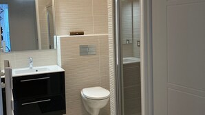 Ein modernes Badezimmer mit einem weißen Waschbecken, einer Toilette und einer Duschkabine aus Glas.