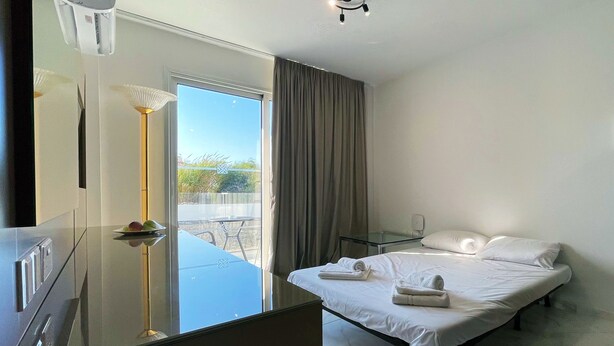 Hotelkamer met een bed, een glazen tafel, een spiegel en uitzicht op het omliggende landschap.