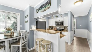 Una cucina moderna con mobili bianchi, un piano di lavoro in granito e una grande decorazione a forma di pesce al muro.