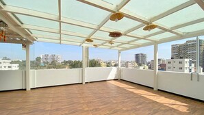 Un balcón abierto con piso de madera y techo de vidrio, que ofrece vistas de la ciudad.