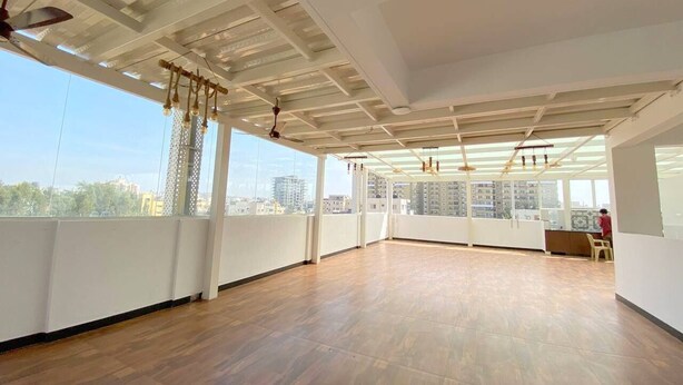 Una habitación amplia con piso de madera, ventanas grandes y un ventilador de techo.