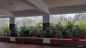 Un espacio interior amplio con ventanas grandes, plantas en macetas y piso de baldosas.