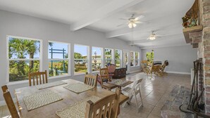 A spacious dining area with large windows, wooden furniture, and a brick fireplace.