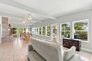 Un salón espacioso con chimenea, ventanas grandes y una zona de estar confortable.