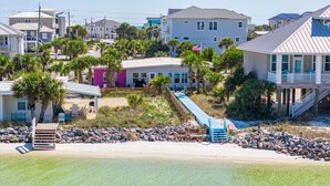 A beachfront property with a wooden deck, a small pool, and a staircase leading to a covered area.