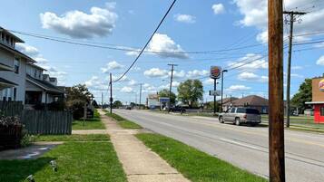 A suburban street with a sidewalk, houses, a road, and a Burger King sign.