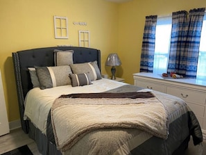 A bedroom with a bed, bedside tables, a lamp, and a window with curtains.