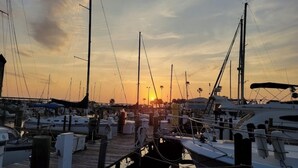Un port de plaisance où des bateaux sont amarrés à des quais en bois, au coucher du soleil.