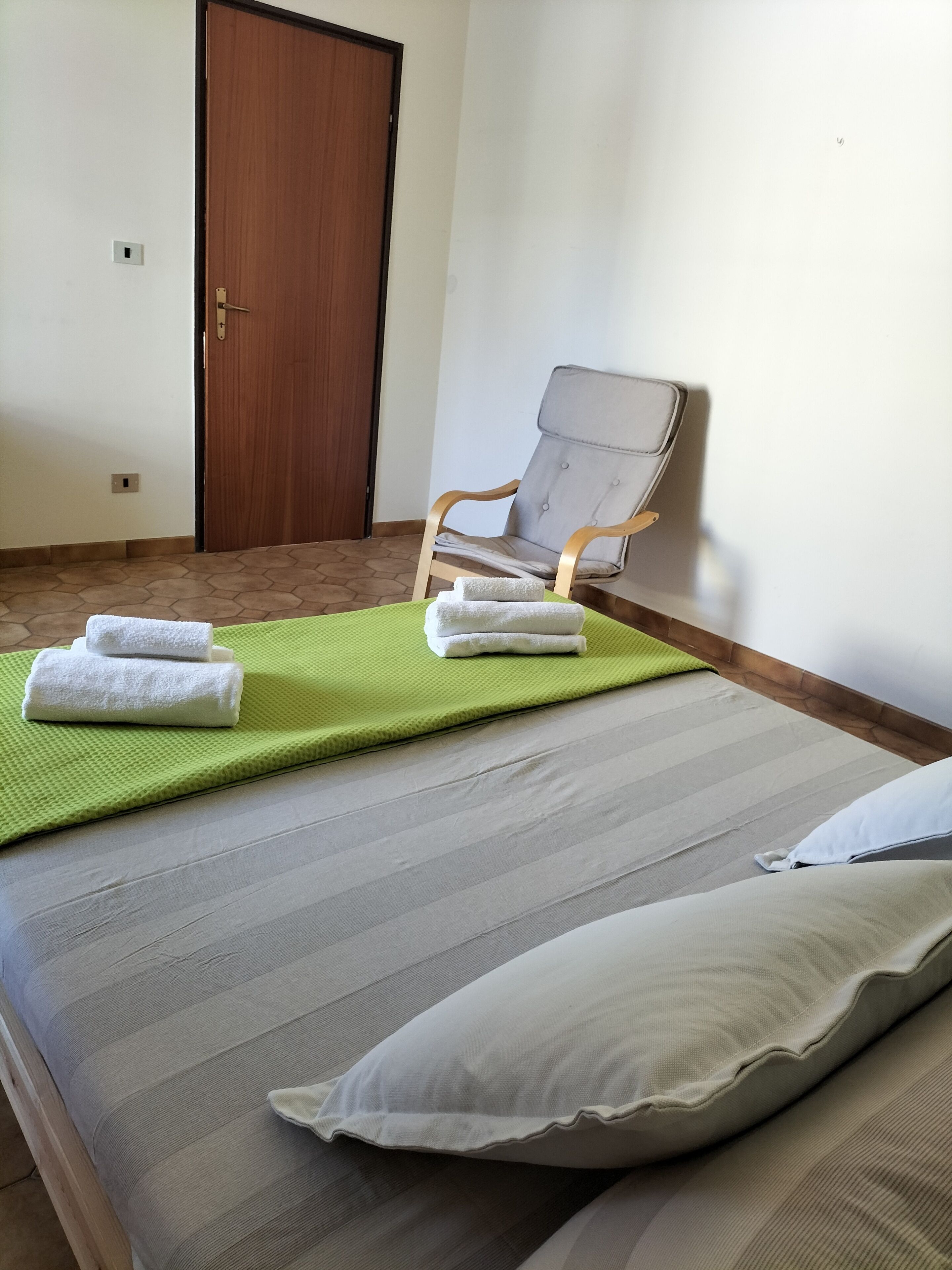 Una stanza con un letto, una sedia e una porta.