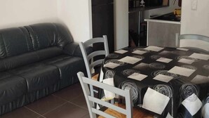 Un espace de vie compact comprenant une table à manger, des chaises, un canapé et un coin cuisine.