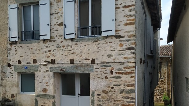 Un bâtiment en pierre de deux étages, avec des volets blancs, une petite porte d’entrée et un panneau indiquant clairement le numéro « 5 ».