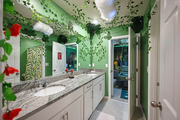 A bathroom with a green wall, a marble sink, and a mirror. - 9Br Villa w Theme Rooms/Pool/Games/Conservative view@Solara (Kissimmee)
