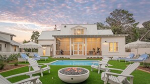 Un patio trasero con piscina, sillas de descanso y una chimenea.