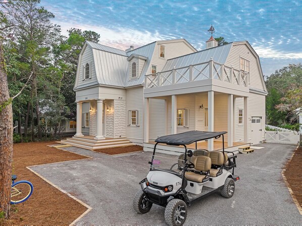 A large, two-story house with a covered porch and a golf cart parked in front. - Beautiful Beach Home Near Seaside with Pool, LSV, Firepit and Pool Table (Santa Rosa Beach)