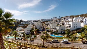 A coastal residential area with white buildings, a winding road, and a swimming pool complex. - Paraíso Benahavís - Private Garden Ground Floor (Benahavís)