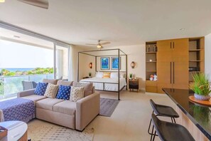 A modern bedroom with a bed, bedside tables, a sofa, and a balcony with a view.