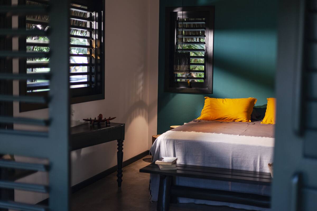 A room with a bed, a nightstand, and a window with blinds.