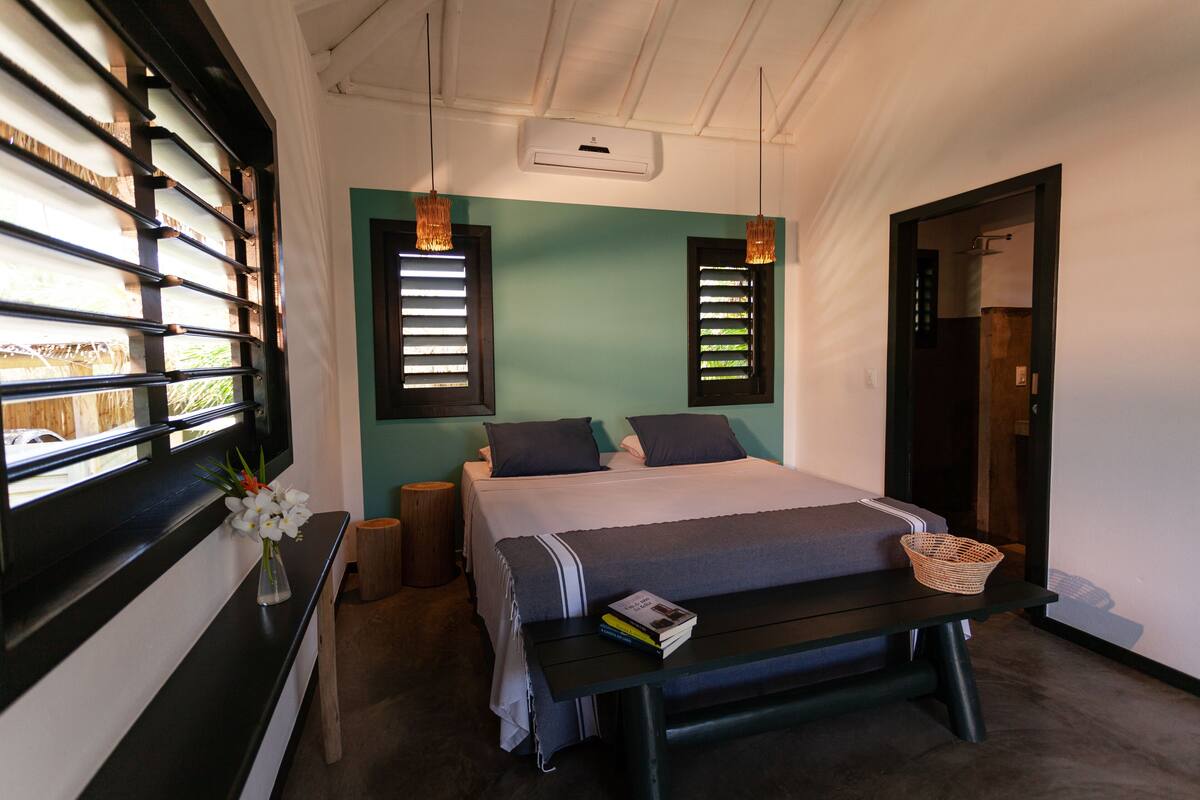 A bedroom with a bed, bedside table, and a window with blinds.