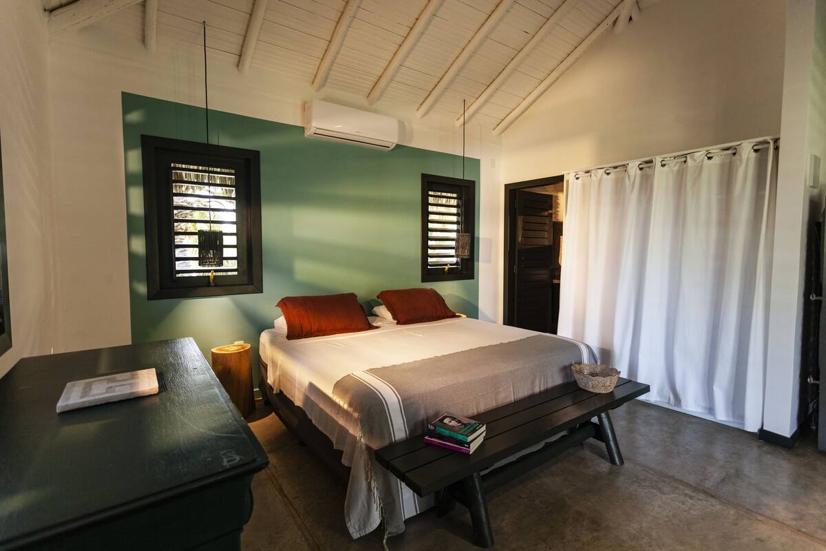 A bedroom with a bed, bedside table, and a bench with a basket.