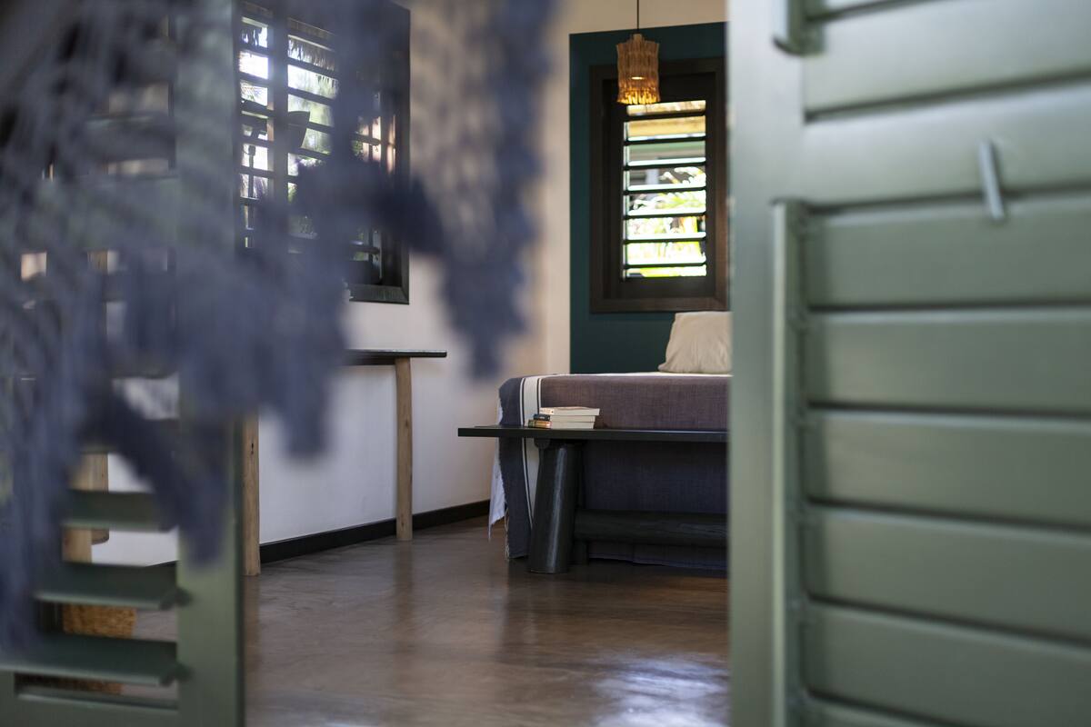 A room with a bed, a table, and a window with blinds.