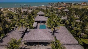 A resort with thatched-roof bungalows, a central pool, and palm trees. - Hotel VilaVeraTheresa  (Fortim)