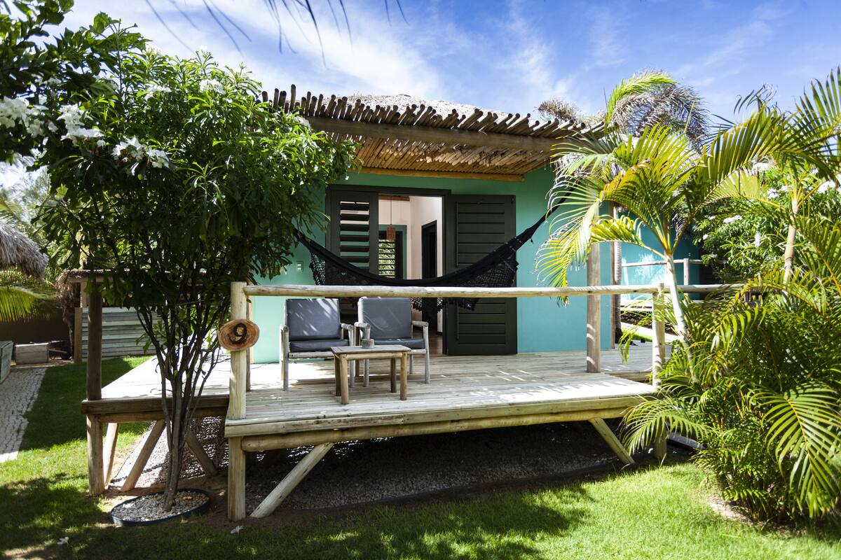 A wooden deck with a hammock, seating area, and a small table.