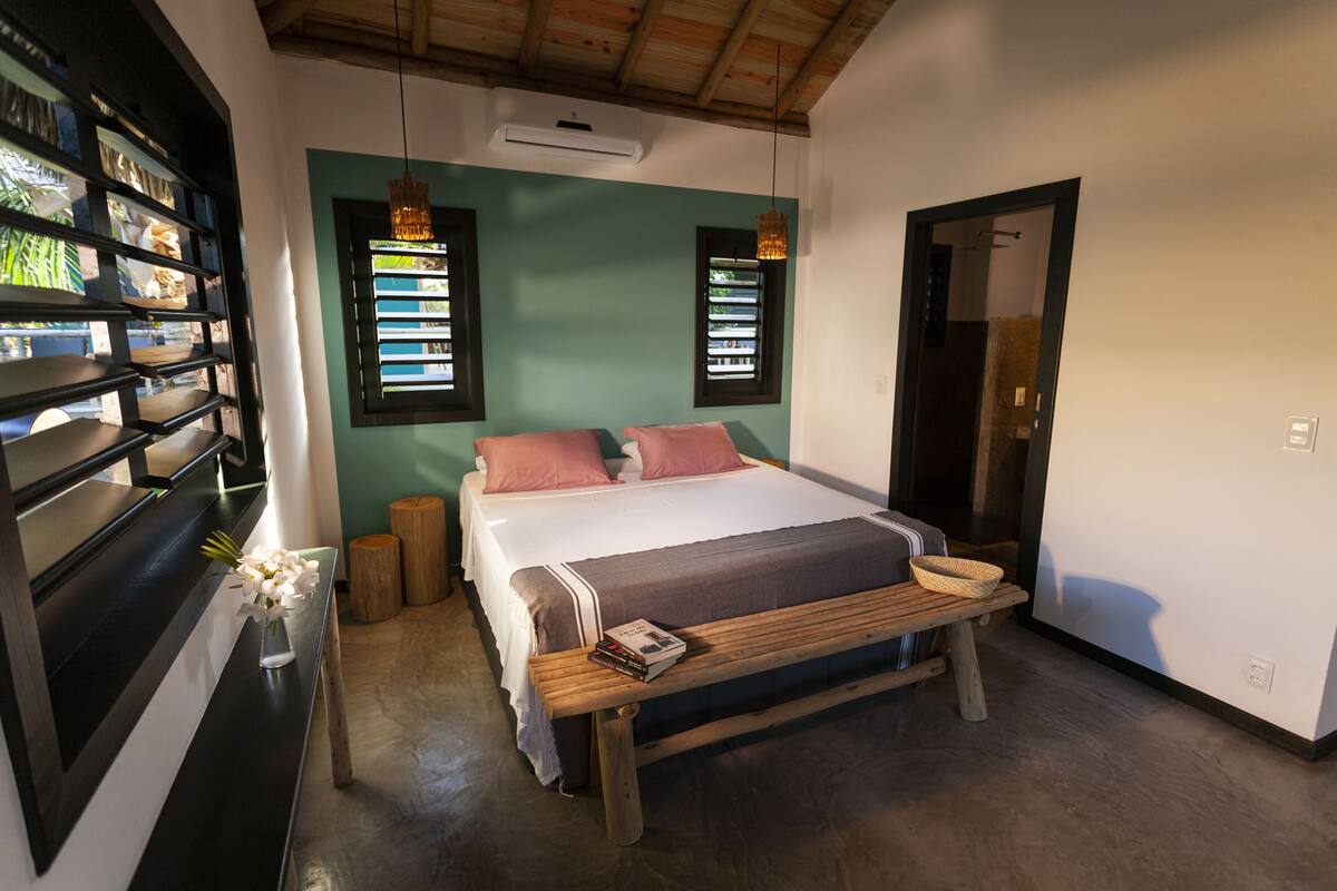 A bedroom with a bed, bedside tables, a wooden bench, and a bookshelf.