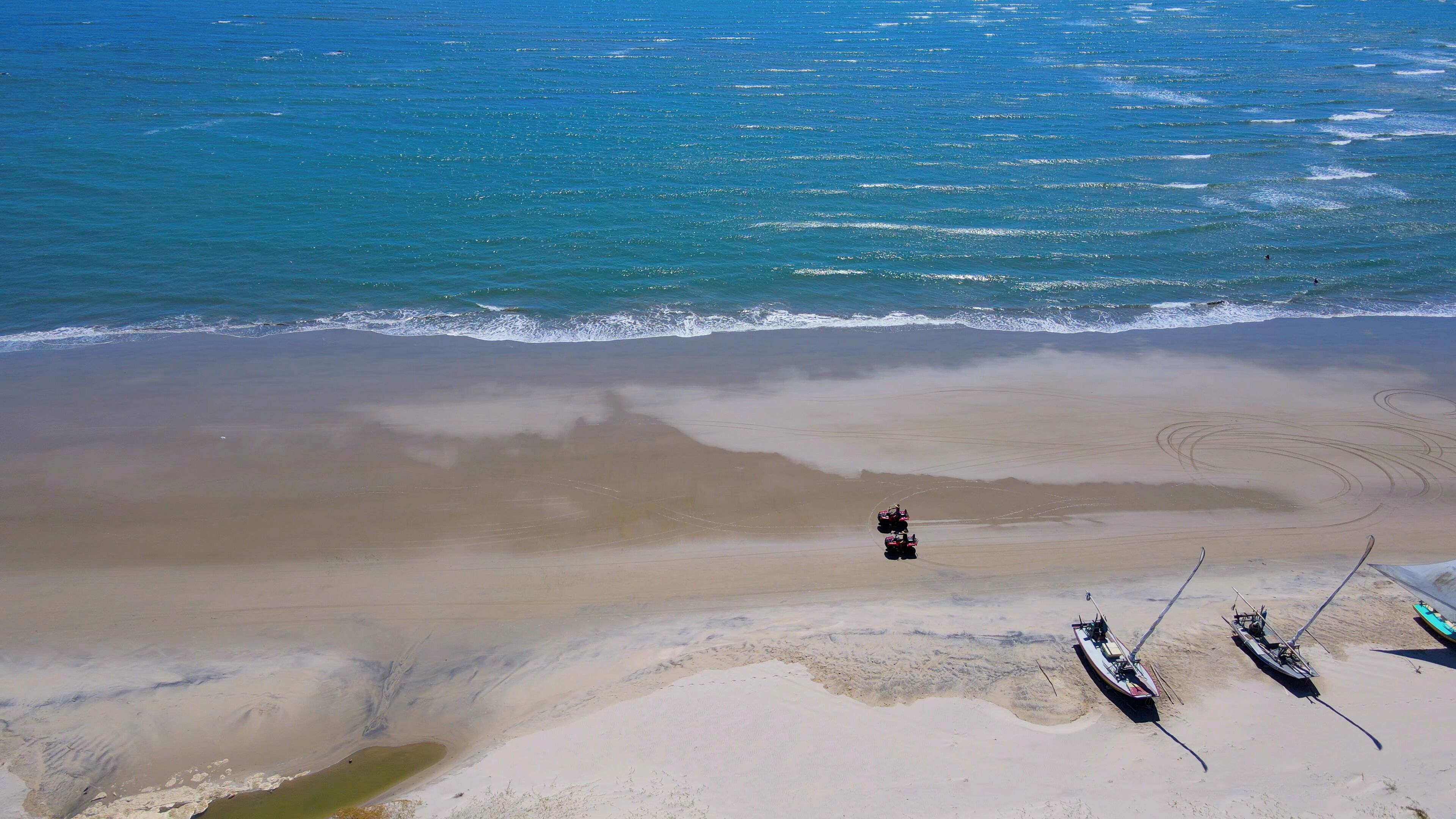 An aerial view of a beach with a few boats and a sandy shore.