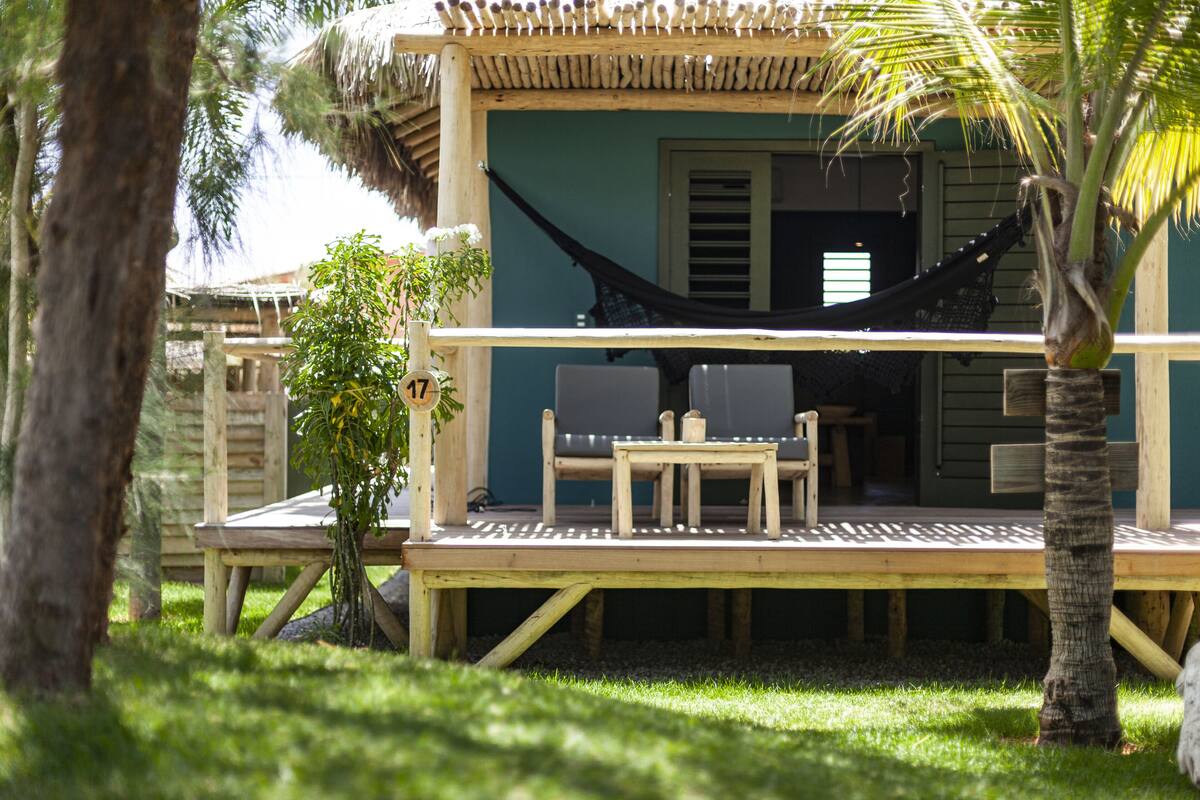 A wooden deck with a hammock, two chairs, and a small table.