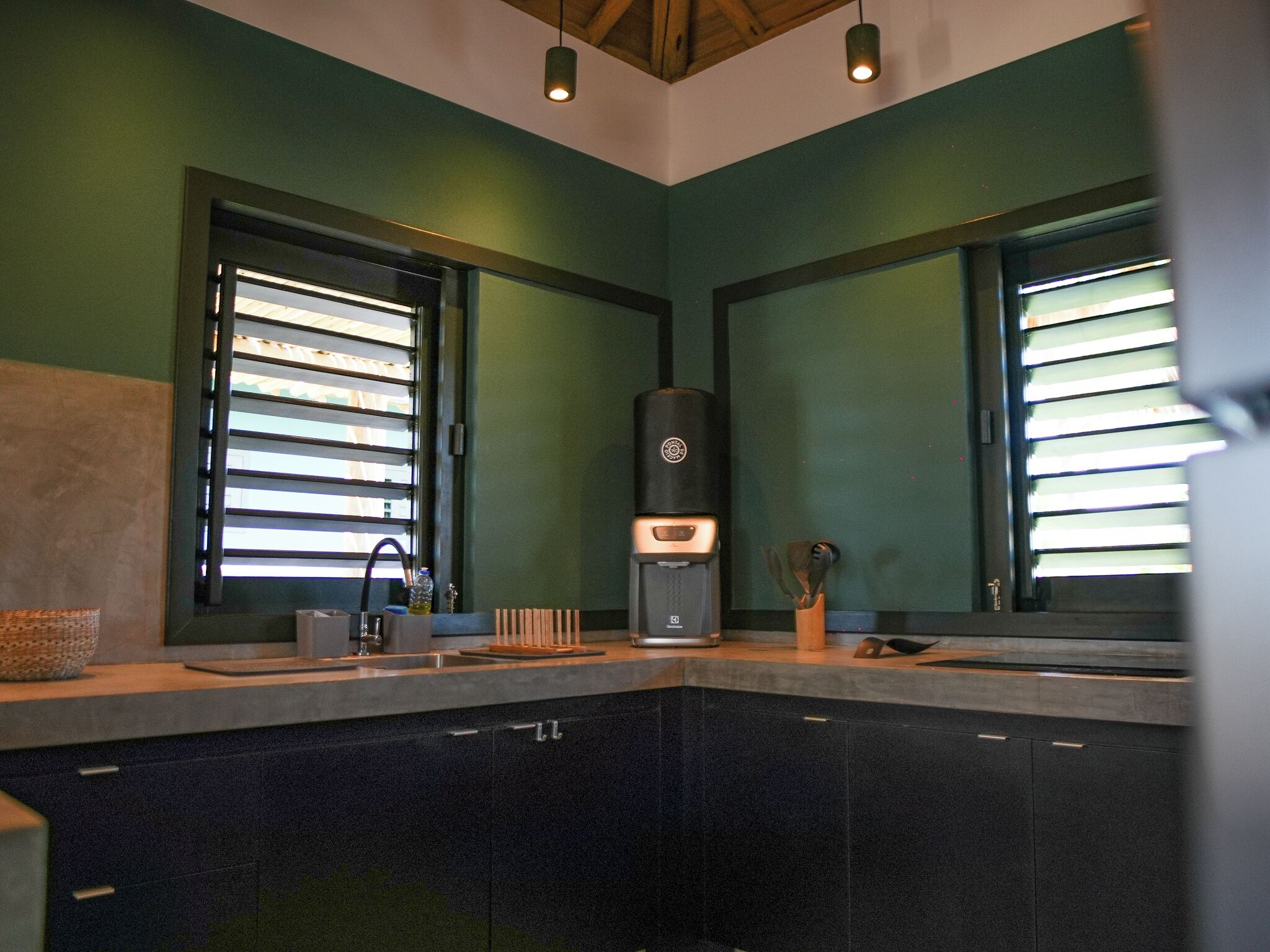 A kitchen with a coffee maker, a sink, and a window with blinds.
