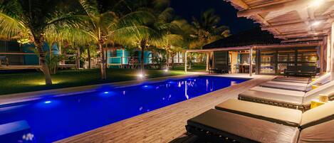 A pool area with lounge chairs and a wooden deck.
