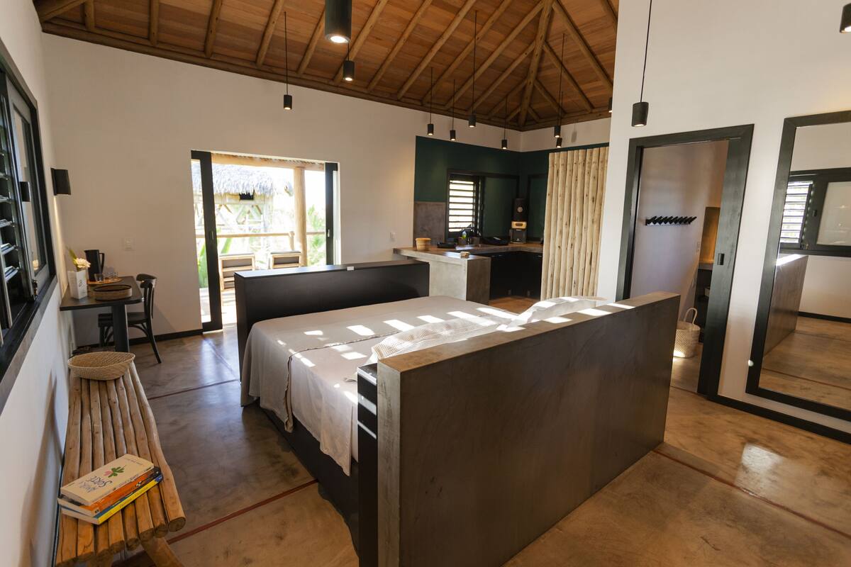 A spacious room with a large bed, a wooden bench, and a small table with a basket.
