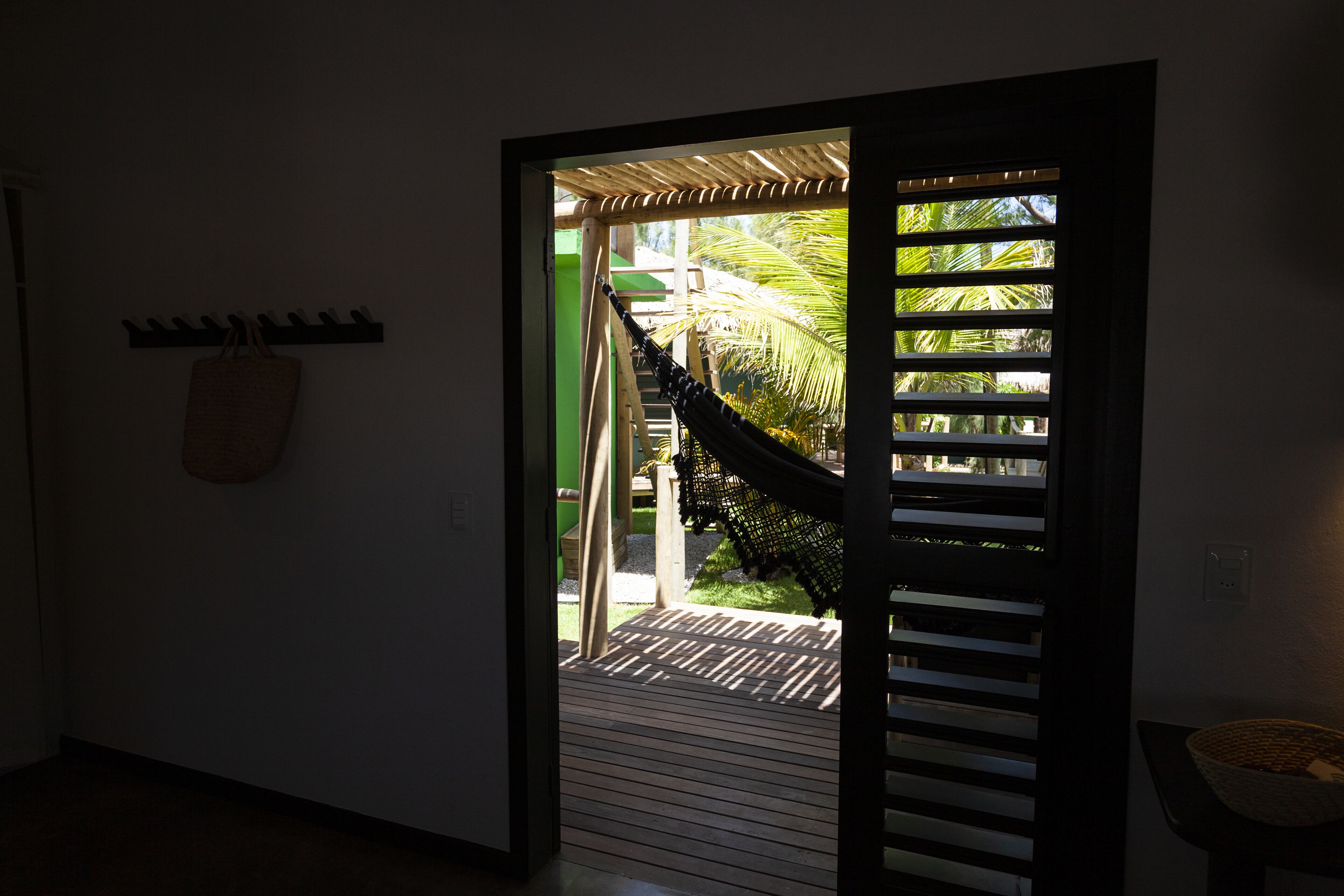 A doorway leading to an outdoor area with a hammock, a wooden deck, and a view of palm trees.