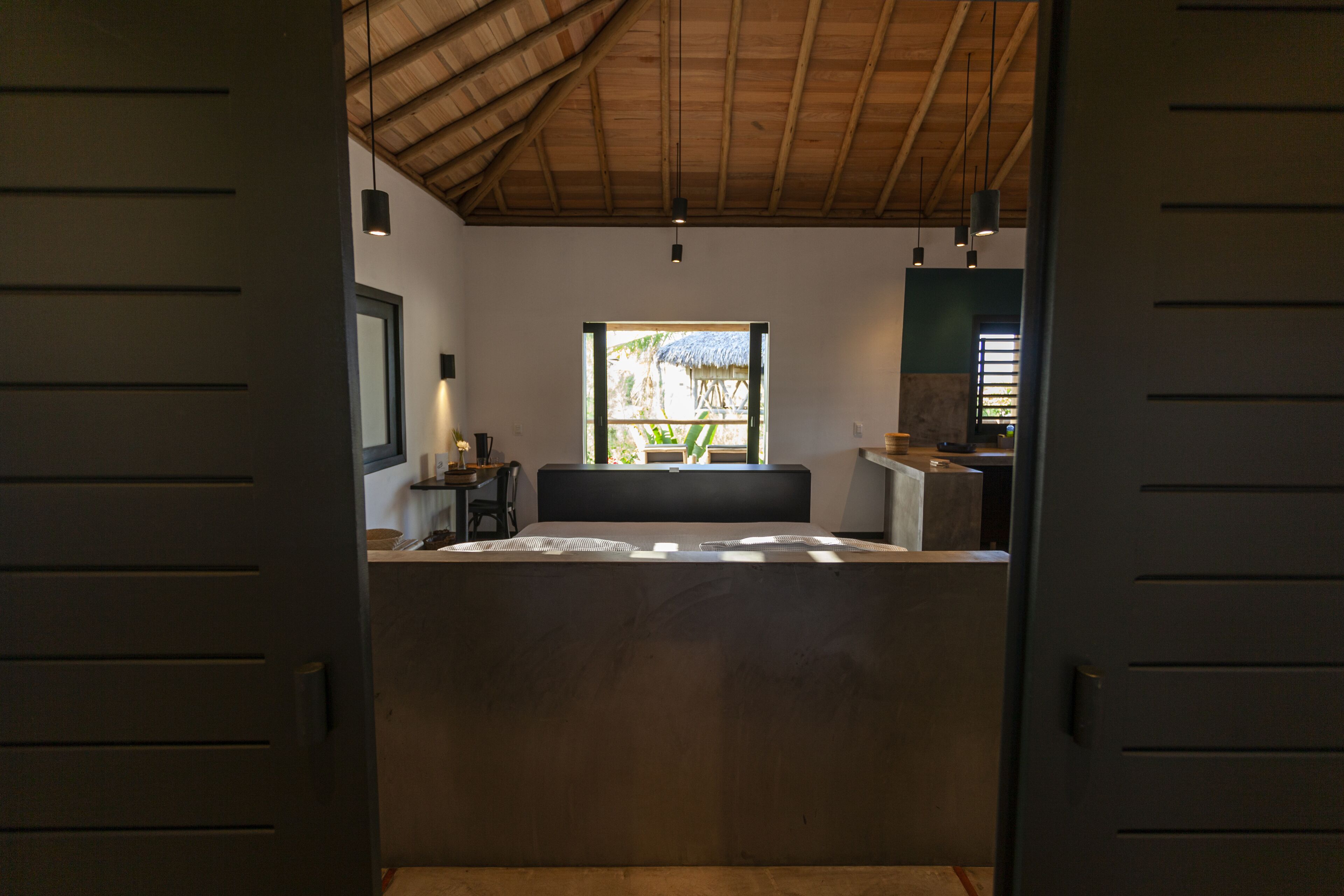 Quarto com cama, escrivaninha, cadeira, janela e vista para o exterior.