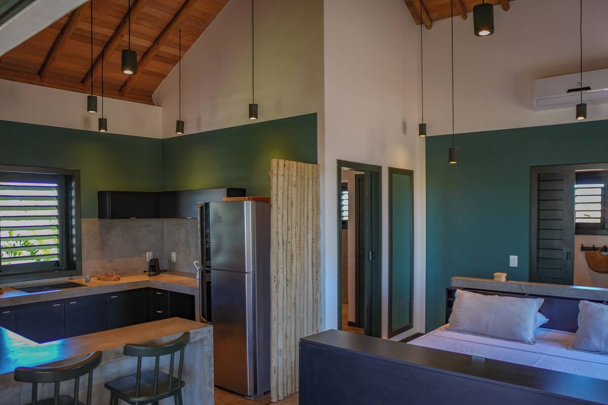 A modern kitchen with a built-in refrigerator, wooden ceiling, and a dining area with bar stools.
