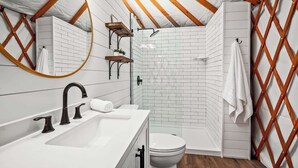 A compact, modern bathroom with a white sink, black faucet, and a shower area with a glass door. - OT 3515H Texas Yurt Haus Horned Frog (New Braunfels)