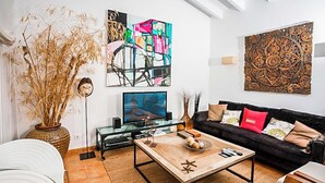 A living room with a sofa, coffee table, TV, and artwork on the wall.