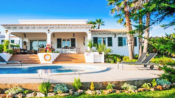 A modern house with a pool, outdoor seating, and a well-maintained garden.