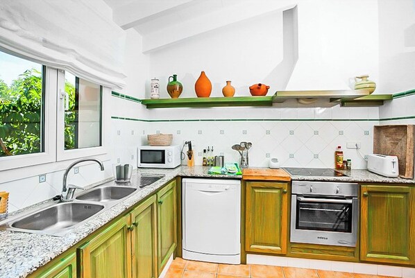 A modern kitchen with green cabinets, a dishwasher, an oven, and a microwave.