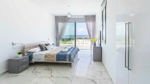 Una camera moderna con un letto, un comodino e vista sul mare.