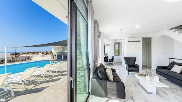 Un soggiorno moderno con vista piscina, un divano, un tavolino e una poltrona.