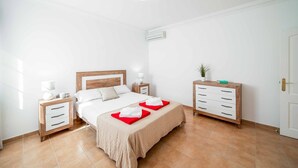 A hotel room with a bed, bedside tables, a dresser, and a potted plant. - Villa Pargo - Three Bedroom Villa, Sleeps 6 (Playa Blanca)