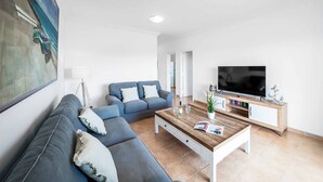 A modern living room with a blue sofa, a wooden coffee table, and a flat-screen TV on a wooden stand. - Villa Pargo - Three Bedroom Villa, Sleeps 6 (Playa Blanca)