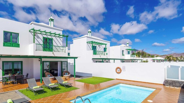 Een moderne villa met een zwembad, terras en uitzicht op de bergen.