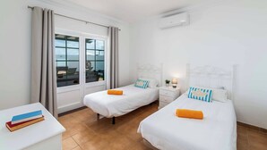Une chambre d’hôtel avec deux lits, une petite table et une fenêtre avec des rideaux.