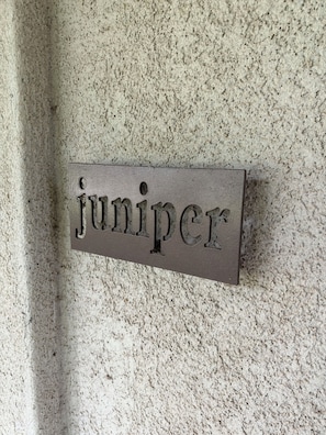 Eine strukturierte Wand mit einem rechteckigen Schild, auf dem 'juniper' steht.